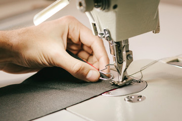 Close-up man hands sewing fabric on sewing machine
