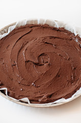 Glutenfree, flourless French Tarte au Chocolat or chocolate tarte made with chocolate, cocoa, butter, almond flour and sugar in tarte cake tin or cake pan before baking on white background