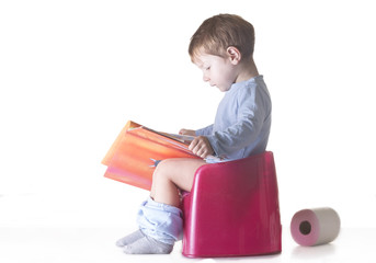 Toddler sitting on chamber pot reading story book
