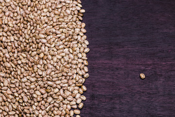 Carioca beans grains on the left side of the frame and a single bean on the right on a purple...