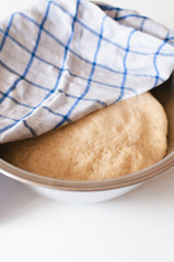 Yeast and white wheat flour dough after rising in bowl for homemade traditional German Kaiser rolls or Austrian Vienna rolls on white wooden background