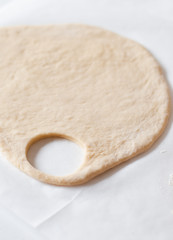 Yeast and white wheat flour dough after rising for homemade traditional German Kaiser rolls or Austrian Vienna rolls on parchment paper on white wooden background