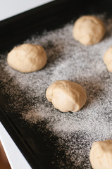 Unbaked, rolled traditional German Kaiser rolls or Austrian Vienna rolls homemade from yeast dough with white wheat flour on flour dusted baking sheet before final rise and before baking