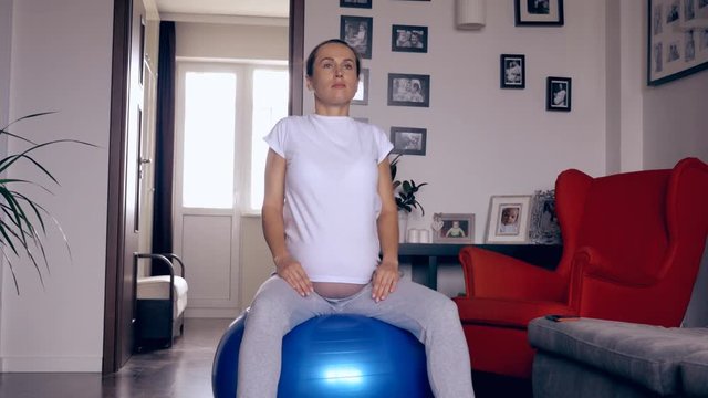 Pregnant woman exercising on fitball at home