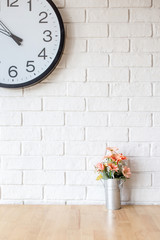 white wall with clock and decorative flower wooden table