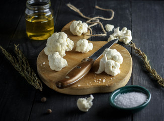 cauliflower on a wooden cutting board with salt, rozmarine and knife