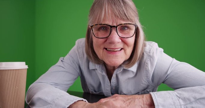 Closeup of elderly lady talking to camera isolated on green chroma key composite