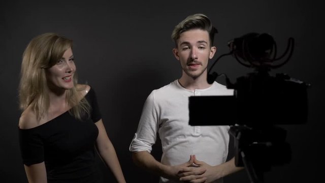 Young beautiful woman and man talking to camera and presenting their video blogging contest in social media