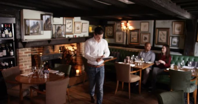 4K Portrait of smiling restaurant owner, taking customer orders with a tablet computer