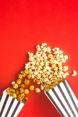 Popcorn in paper bag scattered on red background top view copy space
