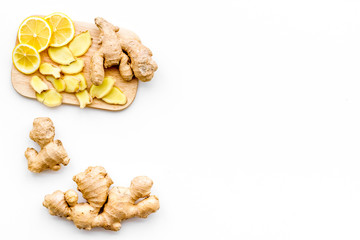 Fresh ginger root and lemon slices pattern on cutting board on white background top view copy space