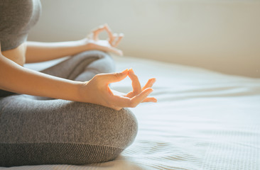 Woman sitting on bed practicing doing yoga meditating,workout after waking up at home,Healthy and  lifestyle concept