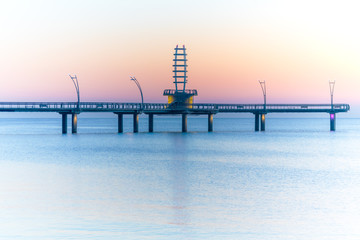 Modern architectural pier with lights glowing against pastel sunrise sky