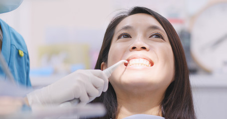 Fototapeta premium Woman dentist working at her patients teeth