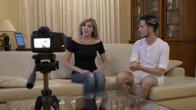 Attractive young couple of vloggers recording a new video tutorial to promote on social media at home on couch