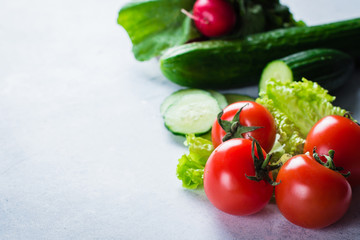 Fresh Raw Spring vegetables. Food Vegetarian Background. Tomatoes, Cucumber, Radishes, Lettuce leaves. Copy Space, top view