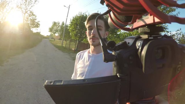 Excited young man spinning and recording a video outside his house with a mobile professional camera about his village in nature