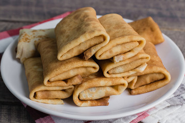 Russian Puncake Crepes stuffed with mushrooms and mozzarella on wooden table background.