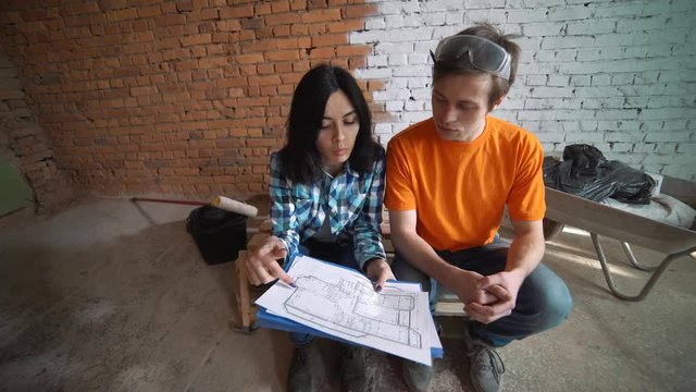 The customer sends the plan of the house to the Builder, explains how to redevelop the house. A man and a woman are watching their house plan.