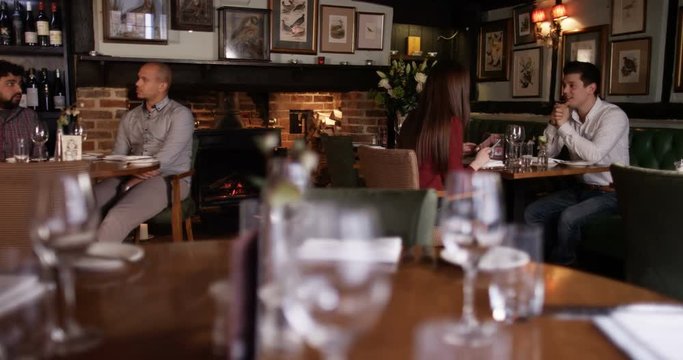 4K Young couple on a date & 2 male friends chatting in the restaurant area of a traditional British pub
