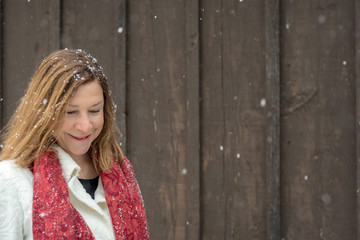 Fototapeta premium beautiful woman standing outside brown wood barn with fresh snow falling