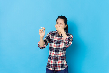 lady holding cigarette standing in blue background