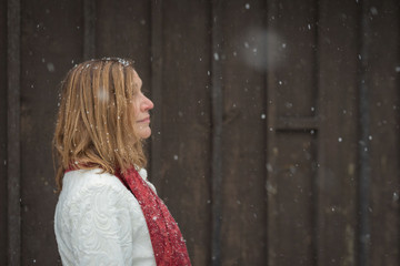 Fototapeta premium beautiful woman standing outside brown wood barn with fresh snow falling