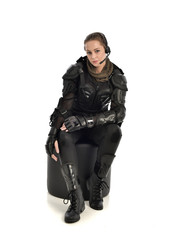 full length portrait of female wearing black  tactical armour, crouching pose, isolated on white studio background.