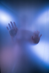 Silhouette of Womans hands behind blue Glass