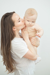 Mother kisses her adorable toddler in cheek, happy motherhood concept.