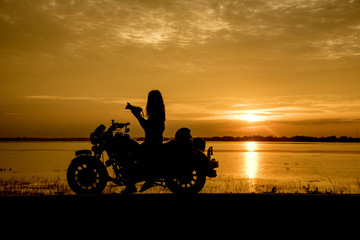 Silhouette woman riding motor bike with sunset. Travel Concept