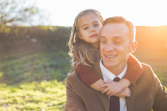 Little girl h hugging her dad from behind with a peaceful look on her face