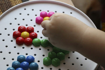 children's mosaic. the child lays a flower out of a colored plastic mosaic. the child's hand holds a bright plastic mosaic piece. training, development of children's motor skills.