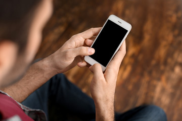 Man using mobile phone indoors, closeup