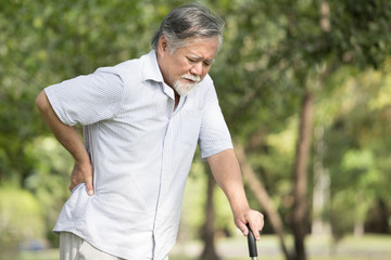 Senior asian man suffering from back pain at outdoor place. Old man holding back because of lumbago