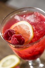 Alcoholic beverage with raspberries lemon and ice on bar counter in pub or restaurant
