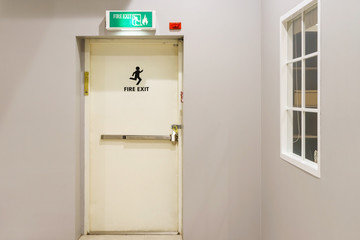 Building emergency exit with exit sign on door and fire extinguisher on the outside of a building