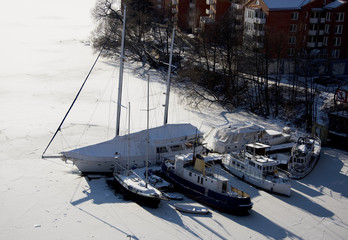 A snowy, cold and sunny view of boats in Stockholm