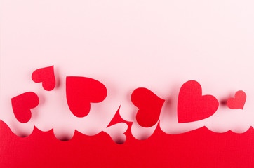 Valentine day background of red paper hearts on pink color backdrop.