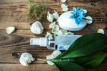 soap and bodyspray with flowers on a wooden background
