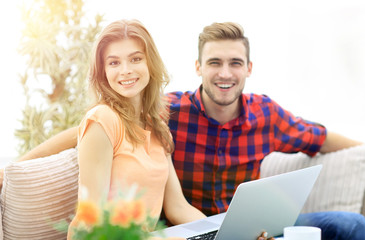 young man and girl sitting in front of an open laptop