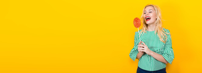 Attractive blonde woman holding colorful lollipop