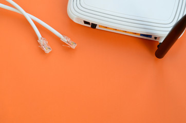 Internet router and Internet cable plugs lie on a bright orange background. Items required for Internet connection - obrazy, fototapety, plakaty