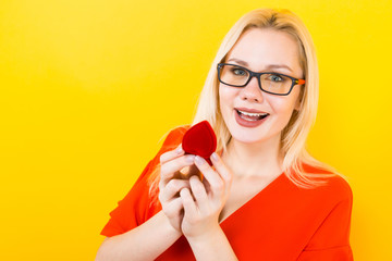 Blonde woman with heart-shaped gift box with ring