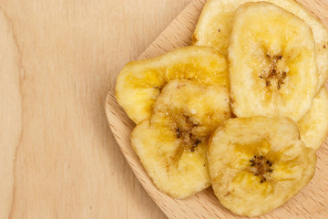 Heap of dried banana chips on wooden spoon
