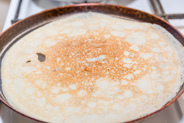 Pancakes are fried in a frying pan. Fried pancakes. Cooking pancakes. Russian folk dish. Maslenitsa.