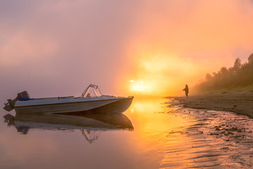 boat on the banks of the foggy river at dawn. beautiful mystical landscape with a fisherman and a boat on the river