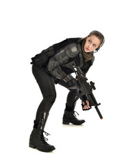 full length portrait of female wearing black  tactical armour, crouching pose holding a weapon, isolated on white studio background.