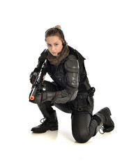 full length portrait of female wearing black  tactical armour, crouching pose holding a weapon,...