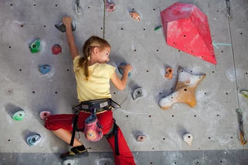 Foto op Canvas little girl climbing a rock wall indoor. © altanaka